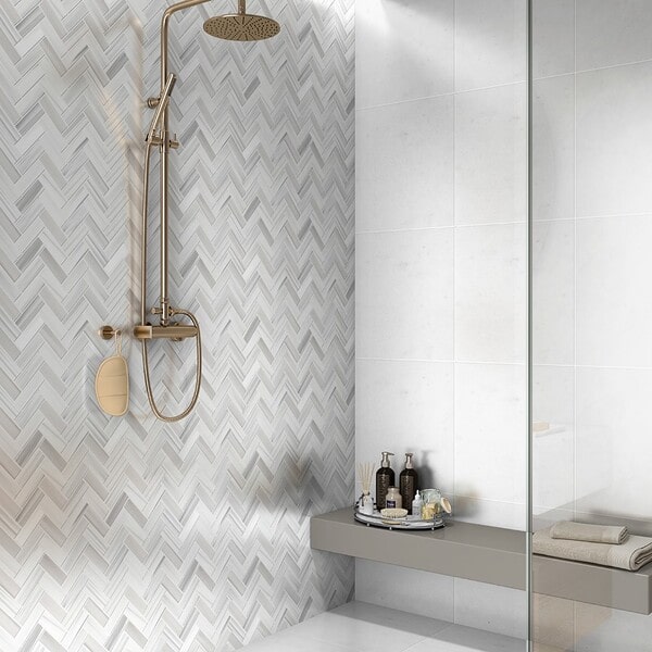 White herringbone mosaic tiles installed on the shower walls of a modern walk-in shower.